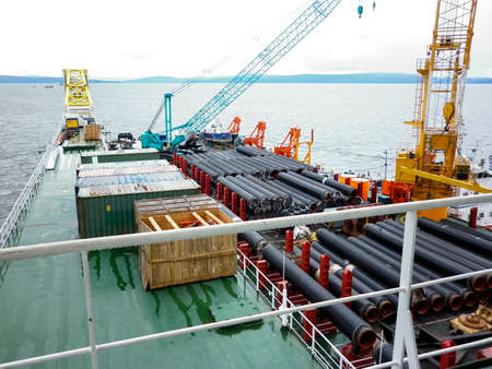 The deck lay barge. Pipes and Lifting cranes on the ship. Equipment for laying a pipeline on the seabed.の写真素材