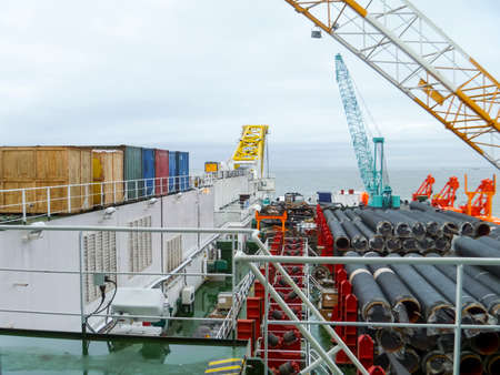 The deck lay barge. Pipes and Lifting cranes on the ship. Equipment for laying a pipeline on the seabed.の写真素材