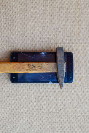 Hammer and smartphone. The screen of the smartphone, a broken hammer. The destruction of the phone.