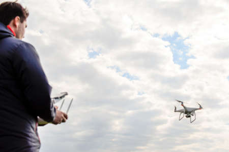 A man with a quadrocopter in his hands. White kvadrokopter prepare for flight.の写真素材