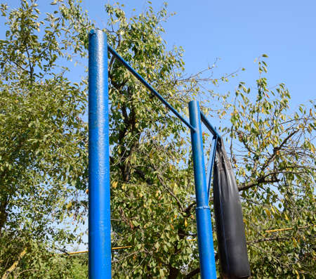 Blue horizontal bar and punching bag. Sports inventory in the backyard. Playing sports in the fresh...