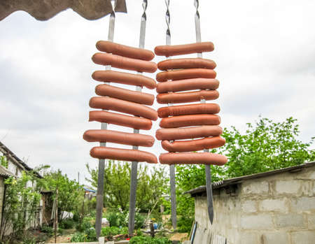Sausages hang on the skewer. Preparation for frying sausages at the stake.の写真素材