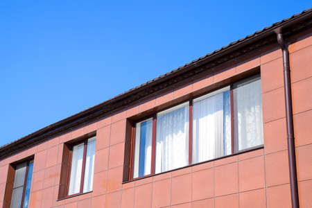 Plastic windows on the house and a spillway system on the roof. House with plastic windows and a...