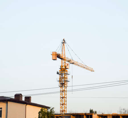 Tower building crane near the new house under constructionの写真素材