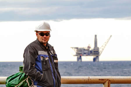 Oilman shift workers on the deck of the ship on the background offshore oil shelf planforms. Work on...