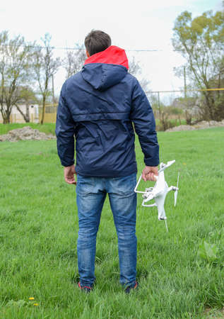 A man with a quadrocopter in his hands. White kvadrokopter prepare for flight.の写真素材