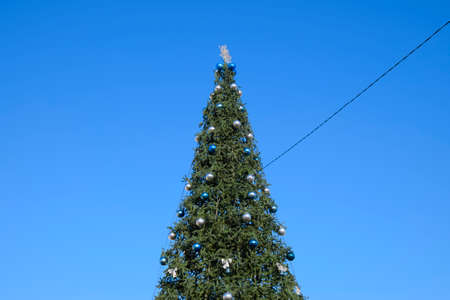 Tinsel and toys, balls and other decorations on the Christmas Christmas tree standing in the open air. Decorations New Year tree.の写真素材