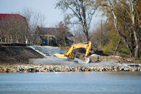 Slavyansk-on-Kuban, Russia - November 8, 2016: Strengthening the embankment of the river in the city. Filling the rubble and leveling the tractor with a scoop.のeditorial素材