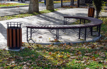 bench in an autumn park. Pavement of tiles and garbage canの写真素材