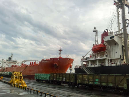 Novorossiysk, Russia - August 11, 2016: Self-propelled port crane. Mobile platform for moving the lifting mechanism. View of the sea and city beach from the port quay. Industrial port with tower cranes and cargo infrastructure.のeditorial素材