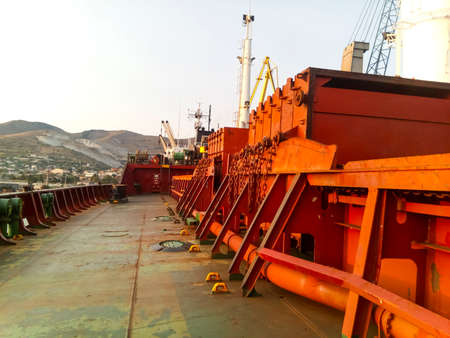 View of the sea and city beach from the port quay. Industrial port with tower cranes and cargo...