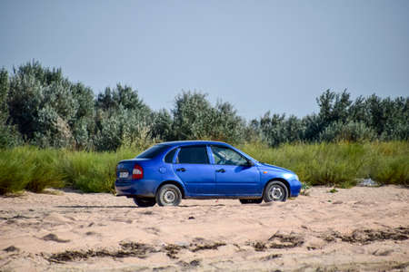 Forests next to the village of Shapsugskaya, Russia - July 30, 2016: A blue car lada kalina under the sun on a sandy road.のeditorial素材