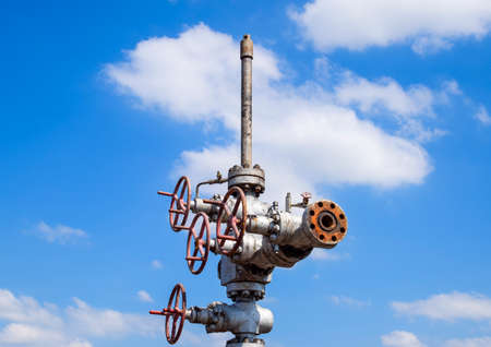 Oil well after repair in mud and puddles. Oil well wellhead equipment. Hand valve with handwheel for...