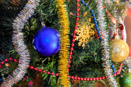 Christmas toys and ornaments on the Christmas tree. Tinsel, balls and toys decorated fir.