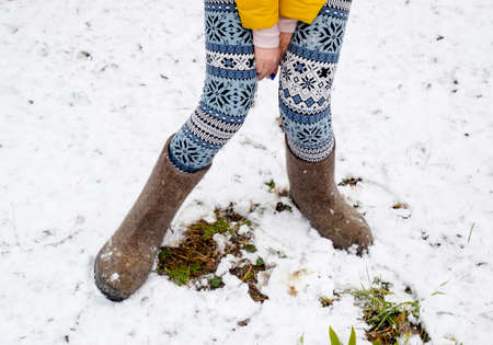 Maiden legs in warm pants and felt boots. The girl in the snow in the winter.