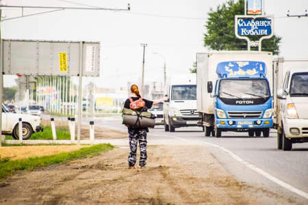 Krasnodar, Russia - June 1, 2017: Hitchhiking. Girl auto-stopper. The girl with the backpack stops the car. Voting on the track.のeditorial素材