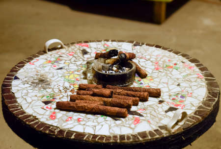 Cigar and ashtray on the table of the glued pieces of pottery. Homemade cigars from leafy tobacco...