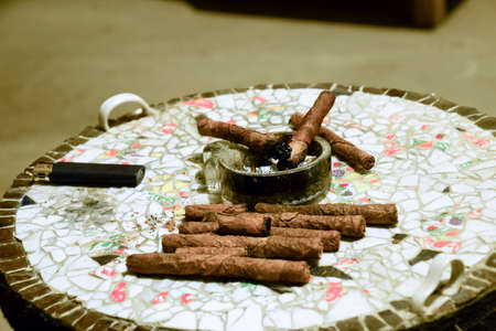 Homemade cigars from leafy tobacco leaves on a ceramic table. Ashtray and cigars.の写真素材