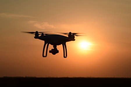 Quadrocopters silhouette against the background of the sunset. Flying drones in the evening sky.