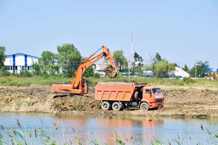 Krasnodar, Russia - June 27, 2016: Excavator pours clay into the truck body. Quarry with clay.