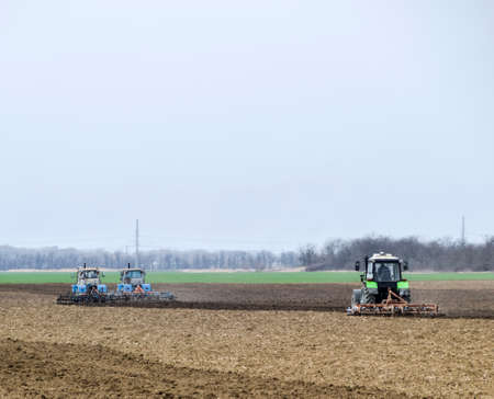 Lush and loosen the soil on the field before sowing. The tractor plows a field with a plow.の写真素材