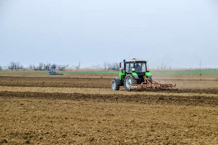Lush and loosen the soil on the field before sowing. The tractor plows a field with a plow.