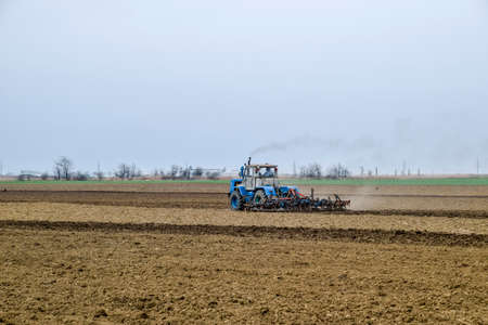 Lush and loosen the soil on the field before sowing. The tractor plows a field with a plow.の写真素材