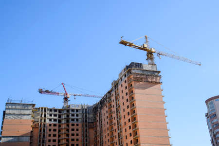 Construction of a new house. Tower building crane against the blue sky and sun. Construction of new buildings with a crane. Tower crane.の写真素材