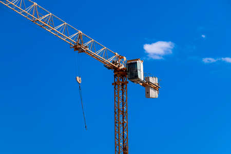Tower building crane against the blue sky and sun. Construction of new buildings with a crane. Tower...