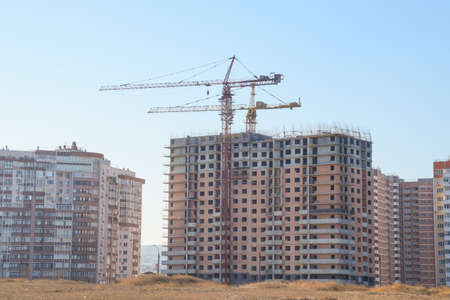 Construction of a new house. Tower building crane against the blue sky and sun. Construction of new...