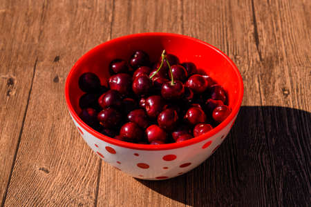 Berries of a sweet cherry on a wooden background in a plastic cup. Ripe red sweet cherry.の写真素材