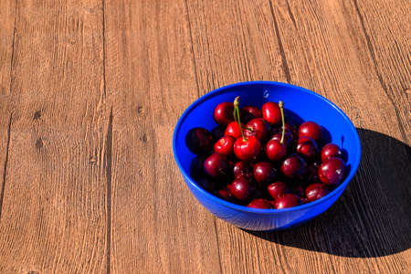 Berries of a sweet cherry on a wooden background in a plastic cup. Ripe red sweet cherry.の写真素材