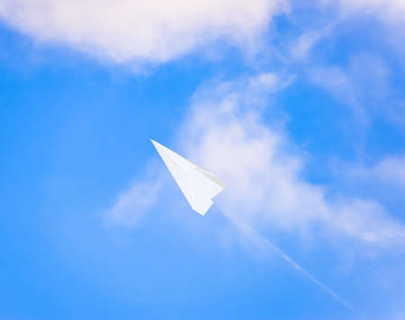White paper airplane in a blue sky with clouds. The message symbol in the messenger.