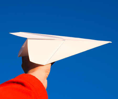 White paper airplane in hand against the sky. A symbol of freedom on the Internet.の写真素材