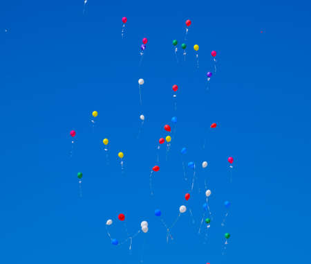 Multicolored balls, filled with helium, fly in the blue sky.の写真素材
