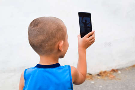 Child with a smartphone. A little boy shoots video on a smartphoneの写真素材