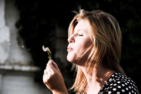 Girl blowing on a dandelion. Blowing of dandelion seeds.の写真素材