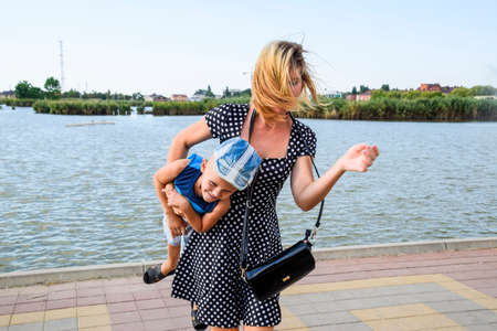 Mom and son are playing on the lake promenade. Walk mother and son.の写真素材