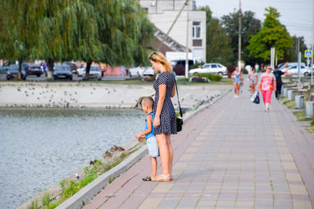 Mom and son are playing on the lake promenade. Walk mother and son.の写真素材
