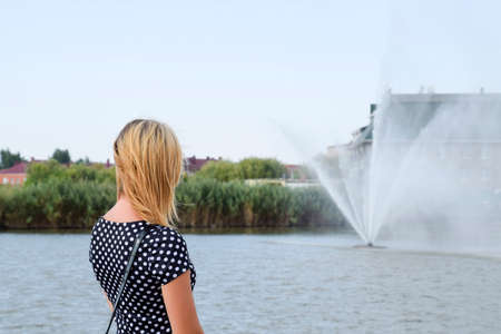 Portrait of a girl against a lake and a fountain. Beautiful blonde.の写真素材