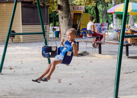 Krasnodar, Russia - August 28, 2017: The little boy swings on the swing himself.のeditorial素材
