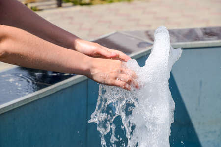 Hand touch the fountain. A stream of water from the fountain is touched by hand.