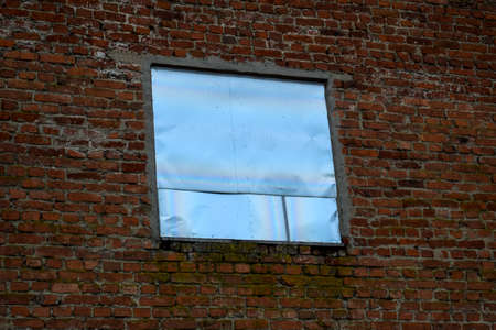 A window on a brick wall covered with an aluminum tin.