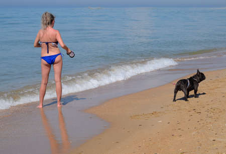 Woman with a dog on the beach by the sea.の写真素材
