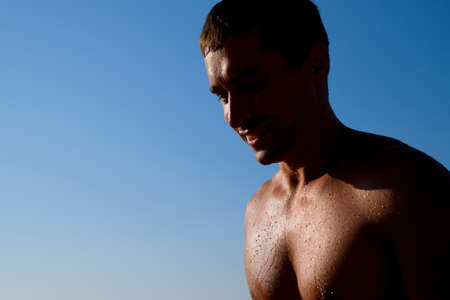 Silhouette of a man against a blue sky and sun. A man in drops of sea water.の写真素材