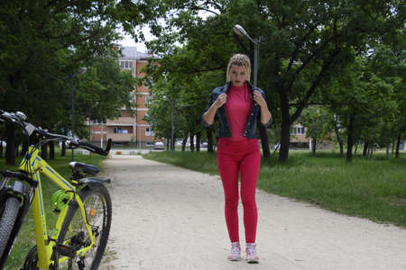 Slavyansk-on-Kuban, Russia - May 15, 2018: Young woman with a yellow mountain bike on a path in a park. A walk on a bicycle in the park. Girl with pigtails from threads.のeditorial素材