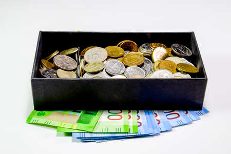 Coins of different denominations in a piggy bank box. Paper rubles under the piggy bank. New banknotes of Russia.の写真素材
