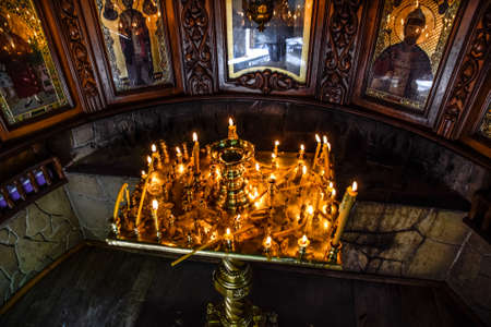 Burning candles on a stand near the icons in the chapel. Attributes of Orthodox Christianity.