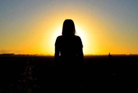 The figure of a woman at sunset. Black silhouette of a woman