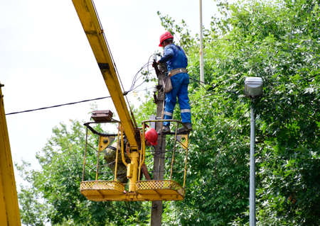 Krasnodar, Russia - August 06, 2018: Electricians repair the wires on the pole with the help of a crane lifter.のeditorial素材